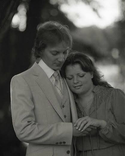 young lady with head on shoulder of young man by a tree