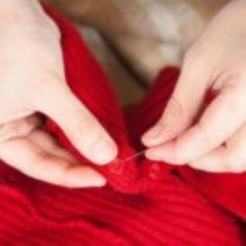 image of hand sewing red sweater
